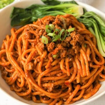 Completed noodle dish topped with crispy browned pork and chopped green onions.