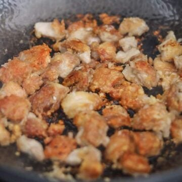 Chicken frying in a pan until golden brown.