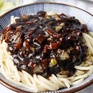 Cooked wheat noodles topped with black bean sauce and sliced cucumber.