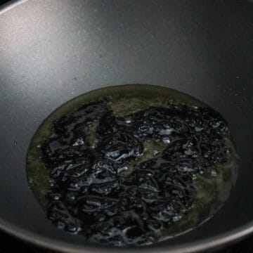 Black bean paste frying in vegetable oil until glossy.