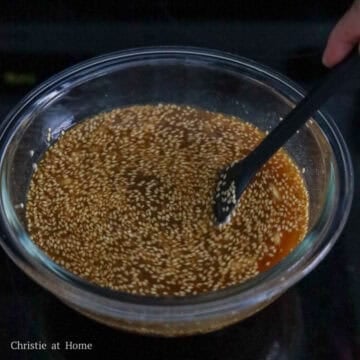 Whisking honey sesame sauce ingredients together in a small clear glass bowl.