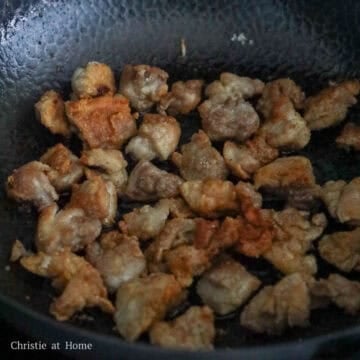 Small batches of cornstarch crusted chicken frying until golden brown and crispy in a hot skillet with vegetable oil.
