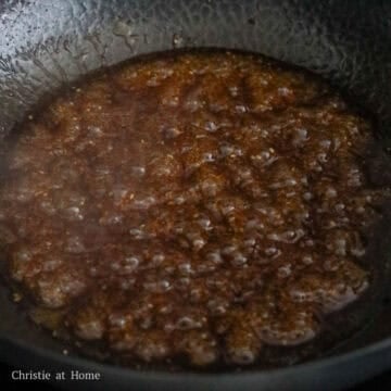 Thickening honey sesame sauce simmering and bubbling gently in a large skillet over medium heat.