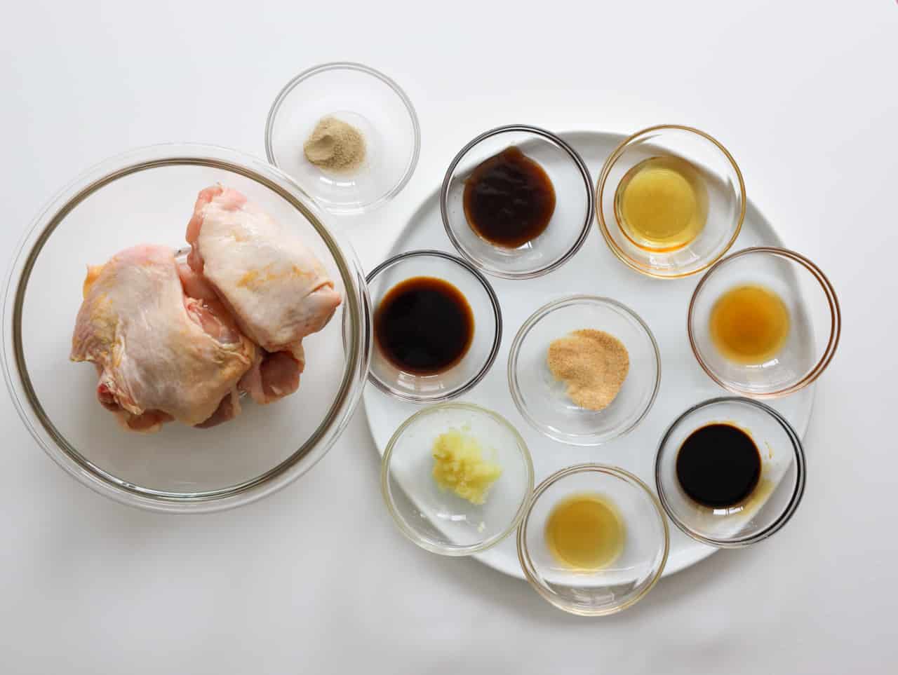 Air fryer soy sauce chicken ingredients with chicken thighs, soy sauces, oyster sauce, honey, sesame oil, Shaoxing wine, ginger, and seasonings.