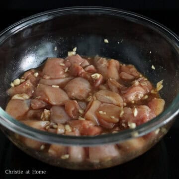 Raw bite-sized chicken thigh pieces coated in soy sauce, egg white, and five-spice marinade.