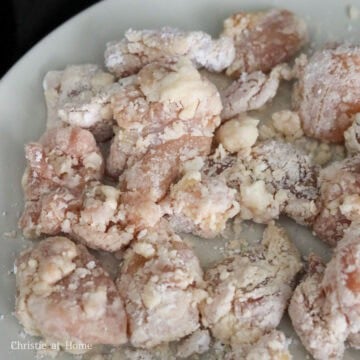 Marinated chicken pieces coated in potato starch with small starch beads on the surface.