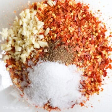 Add dried red chilis into a food processor and grind on HIGH speed until they become small flakes. Transfer the chili flakes into a large heat-proof bowl (made of steel, ceramic or heat-resistant glass) and avoid inhaling the spice. To the same bowl, add minced garlic, Sichuan pepper powder and salt. Set aside.