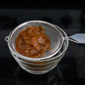 Tamarind pulp being mixed with boiling water. Tamarind paste being strained through a fine sieve.