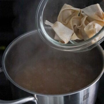 Once the wonton soup reaches boiling point, reduce to medium-high heat and add 5-6 shrimp pork wontons per one serving. Immediately stir so they do not stick to the bottom of the pot. Boil for 3 minutes or until they float to the top.