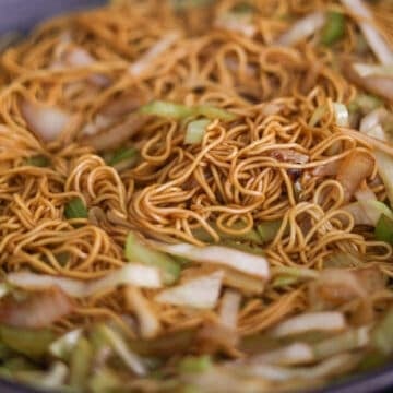 Thick yellow noodles completely coated in a glossy brown sauce with visible flecks of cabbage and celery.