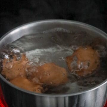 Large eggs simmering in water with salt and vinegar.