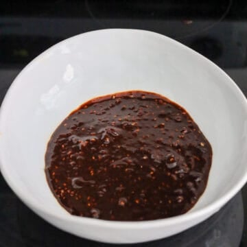 A hand whisked noodle sauce ingredients together in a small bowl.