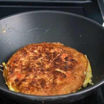 Egg foo young omelet fried until deeply golden brown and crispy on the bottom.