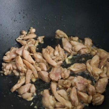 Heat vegetable oil in a large pan on medium-high heat. Fry garlic and marinated chicken until chicken is 75% cooked. Move to the side of the pan.