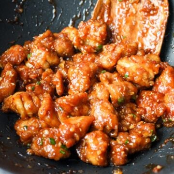 Crispy chicken pieces tossed in glossy glaze and topped with sliced green onions and toasted sesame seeds.