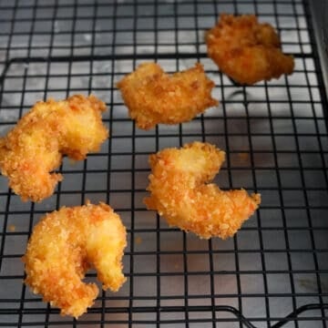 Crispy fried panko shrimp draining on a wire rack