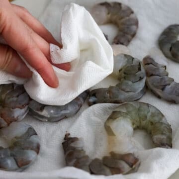 Jumbo shrimp being peeled, deveined, rinsed, and patted dry