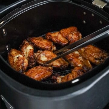 Soy sauce chicken wings being flipped in the air fryer basket