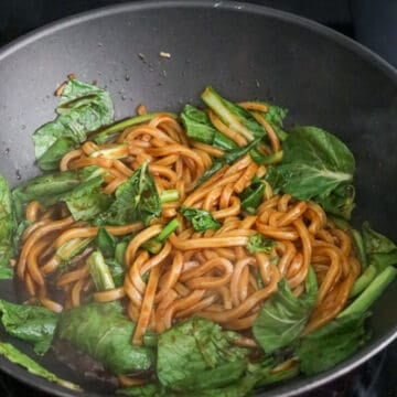 Increase to medium-high heat, add udon noodles with noodle sauce. Mix well and cook until sauce has slightly thickened and isn’t so runny. Toss in greens and cook until they’re softened.
