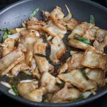 Cooked pork belly slices glazed in a sticky sauce with slightly browned edges and a sesame seed garnish.