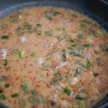 Creamy pink sauce being stirred in a pan with gochugaru, gochujang, sesame oil, and soy sauce.