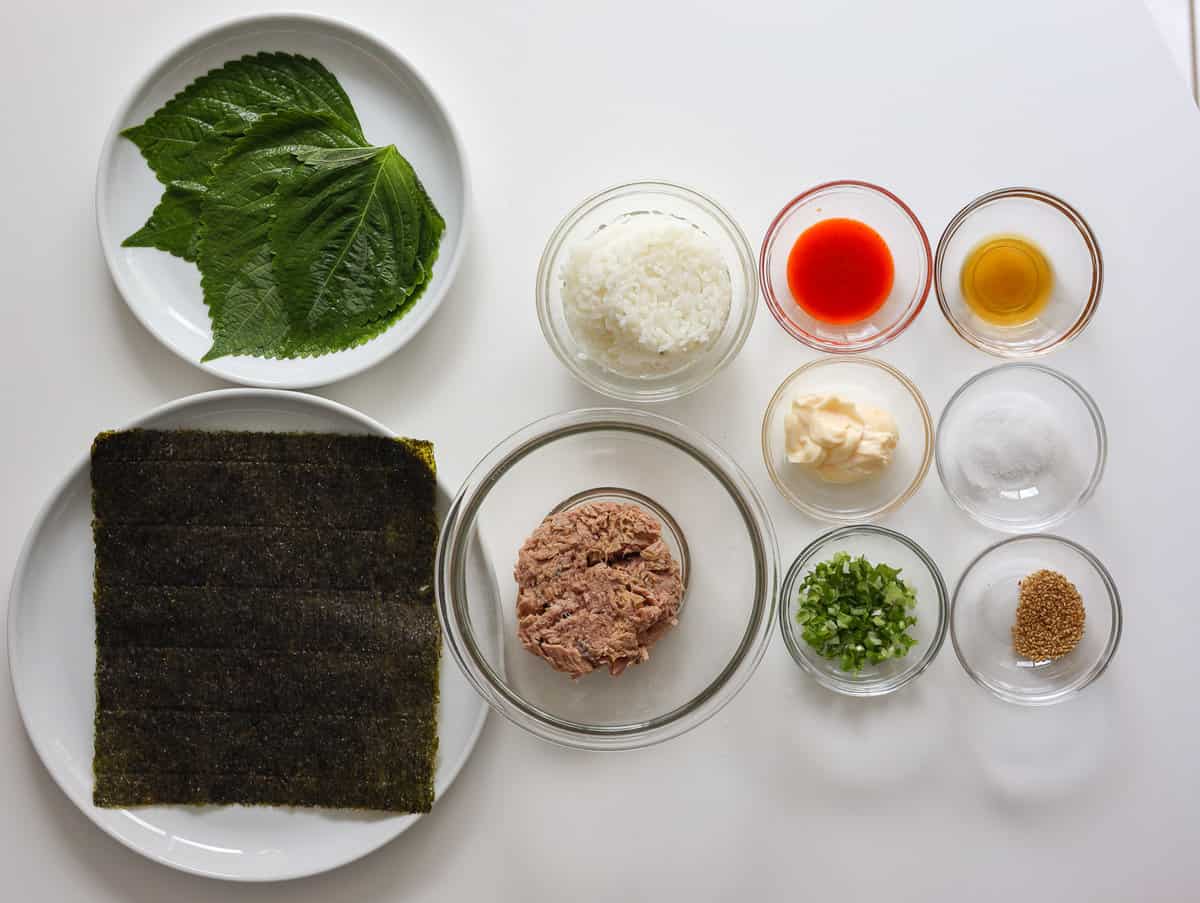 Ingredients for spicy tuna kimbap, including rice, tuna, perilla leaves, seaweed, Kewpie mayo, and seasonings.