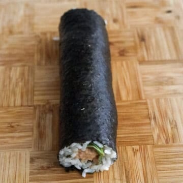 Spicy tuna kimbap tightly rolled and placed seam-side down.