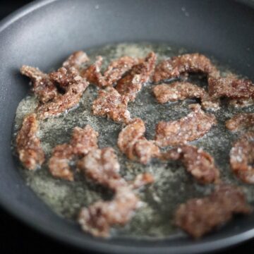 Beef slices frying until golden and crispy.