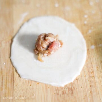 Pork and shrimp filling centered on a dumpling wrapper with moistened edges.