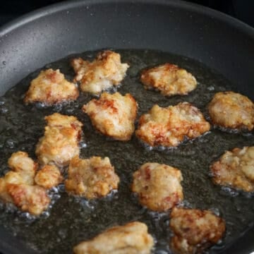 Golden brown chicken pieces bubble in hot frying oil.