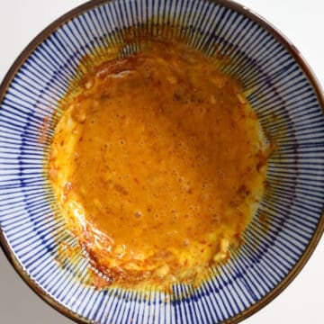 In a large serving bowl, whisk together minced garlic, kewpie mayo, raw egg and the instant ramen soup base powder.