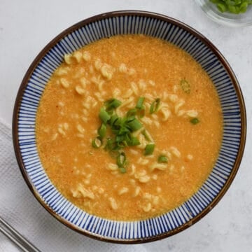 Then pour the rest of the ramen water and ramen noodles into the bowl. Mix the ramen and broth together. Garnish with green onions and enjoy!
