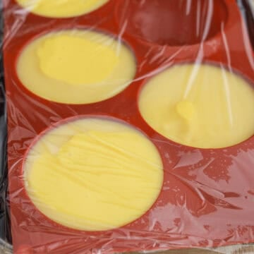 Mango pudding mixture poured into dessert bowls and silicone molds before chilling.