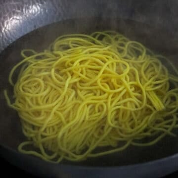 Thick yellow noodles loosening in boiling water.