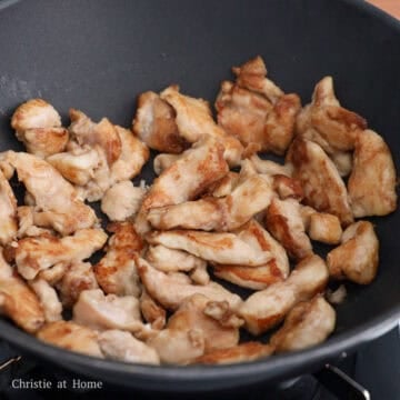 Chicken pieces frying in a hot pan until golden brown and cooked through, then removed.