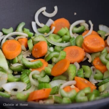Aromatics and vegetables (onion, garlic, carrot, celery) stir-frying in a pan until crisp-tender.