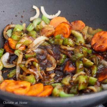 Stir-fry sauce being poured into the pan and gently simmering until slightly thickened.