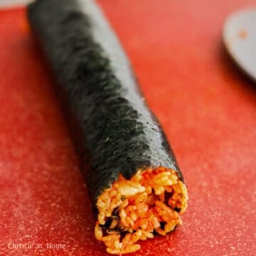 Then gather the end closest to you and firmly tuck in the cheese and roll all the way to the end. Let the roll sit on the nori border so the residual heat can adhere it to the rest of the roll. Repeat this process until you have 3 more rolls.