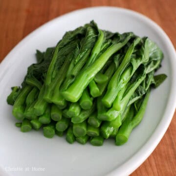 Blanched vibrant green yu choy drained and transferred to a serving plate.