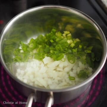 Diced white onion, green onion, and minced garlic sautéing in oil.