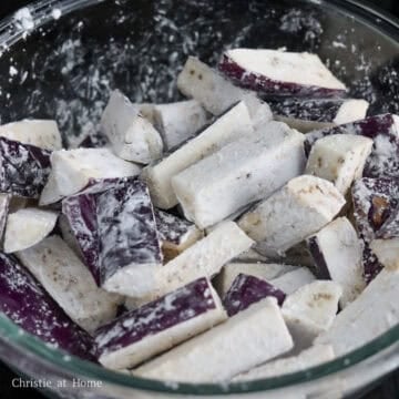 Raw purple eggplant chunks evenly dusted with white cornstarch coating.