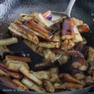 Searing purple eggplant pieces developing golden edges in hot oil.