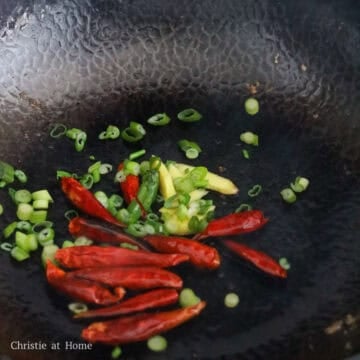 Minced ginger, whole red chilies, and green onions sizzling in oil.