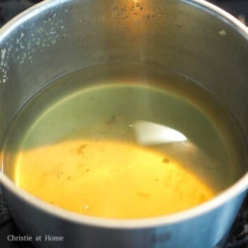 Broth being strained with the kelp and vegetables removed, leaving a clear liquid.