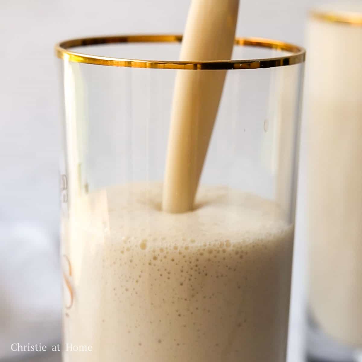 A tall glass filled with smooth yellow banana milk.