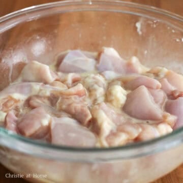 Cubed chicken thoroughly coated in a liquid marinade.