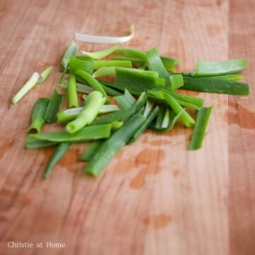 Fresh scallions being washed, patted dry, and sliced lengthwise into long pieces before being cut into segments.