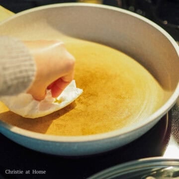 In a 10-inch pan set over medium-low heat, lightly grease it with butter using a clean paper towel.