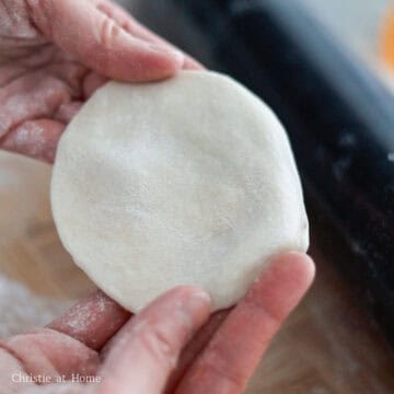 Then re-flour the working surface and roll out one dough ball at a time with a rolling pin into a thin wrapper that is 3-inches wide in diameter. Place the wrappers on parchment paper in a single layer and cover.