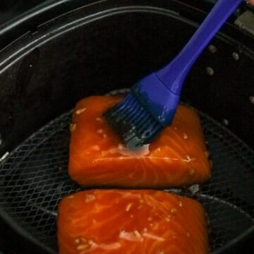 Glazed salmon filets arranged skin-side down in an air fryer basket
